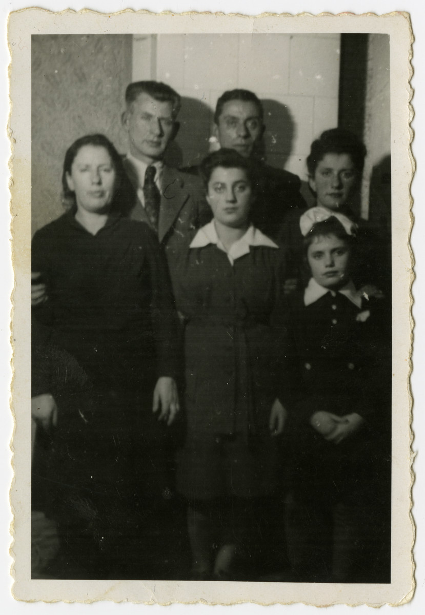 Family portrait of Jewish survivors in Lodz after the war. 

First row (L-R): Abraham Murik and Elias Dawidowicz. Second row (L-R) Taube Dawidowicz, Ida Dawidowicz, Lisa Murik, and Chana Dawidowicz.