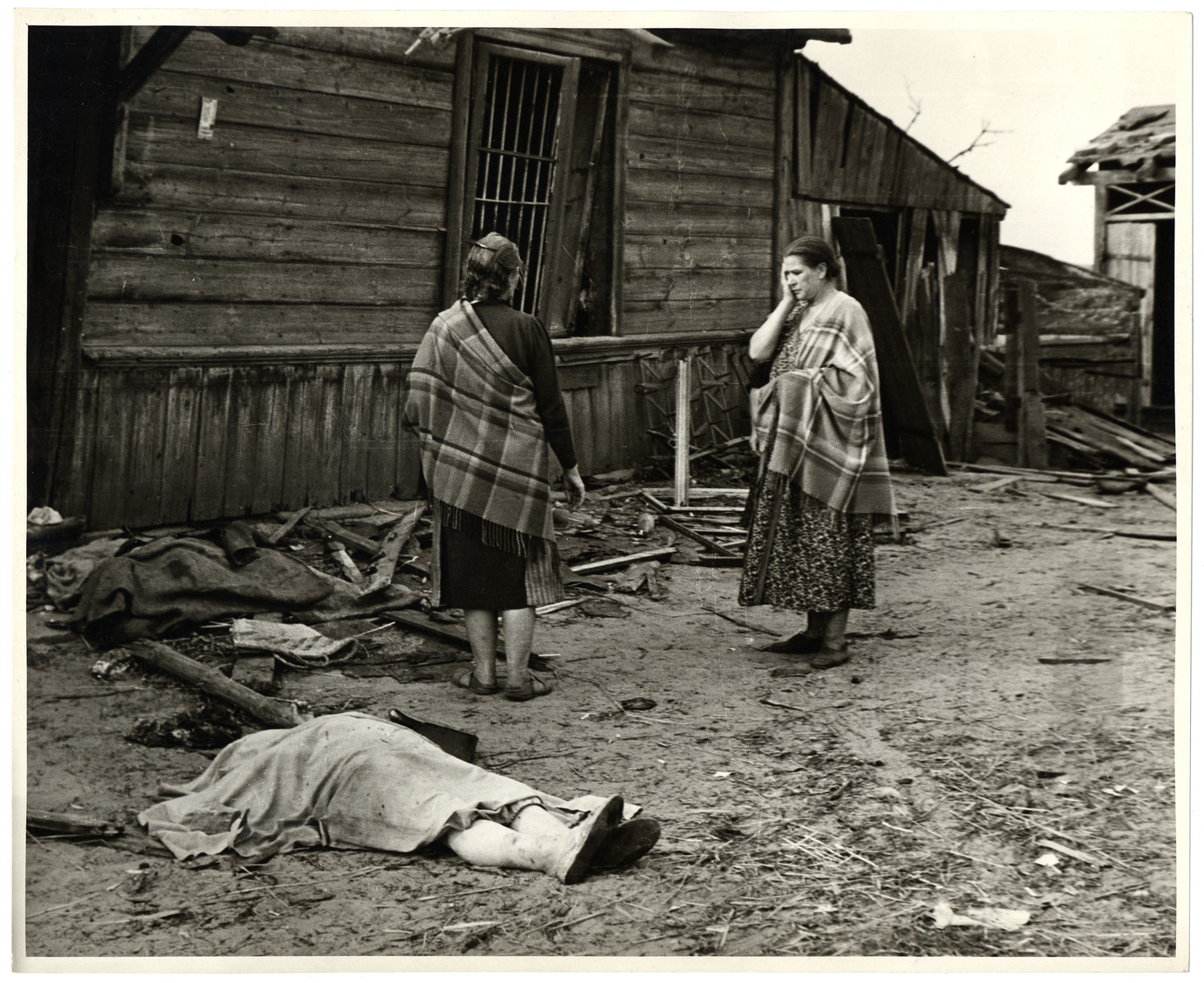 Two Polish women stand horrified after the destruction of their homes by the Germans - in the foreground is the corpse of one of the women killed in the air raid.