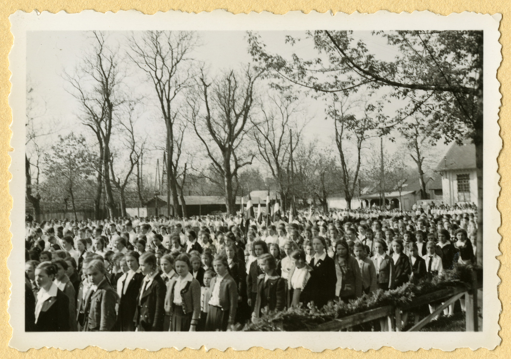 German girls stand at attention at a large outdoor gathering.