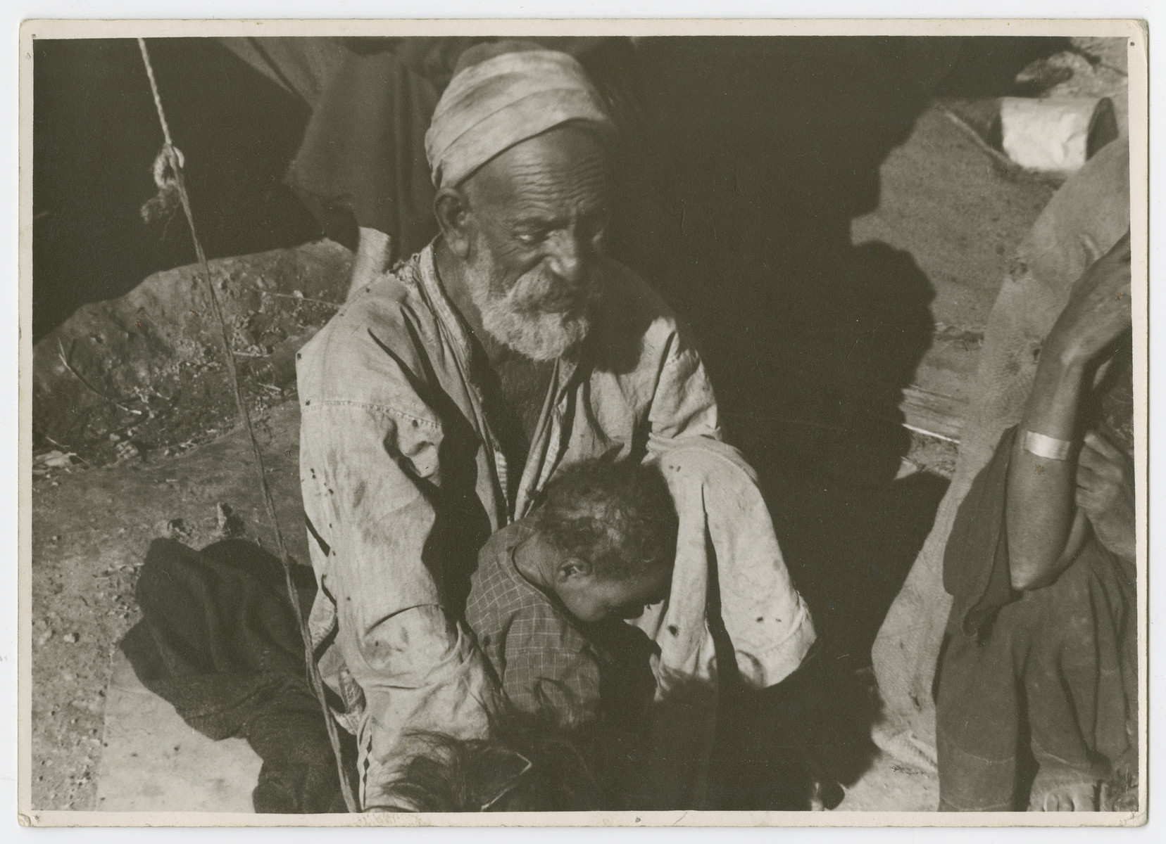 An older man and young child [probably Sephardic] sit outsie a tent.

Photograph is used on page 253 of Robert Gessner's "Some of My Best Friends are Jews."