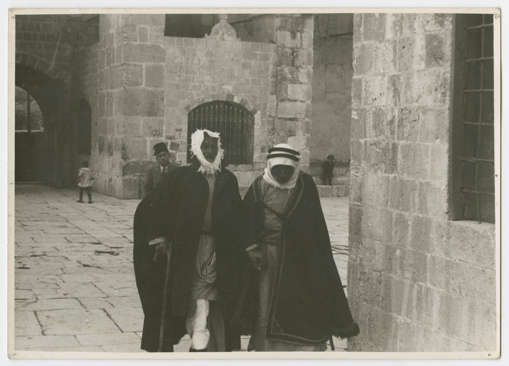 Two Arab men walk through a courtyard, probably in Jerusalem.

Photograph is used on page 242 of Robert Gessner's "Some of My Best Friends are Jews."