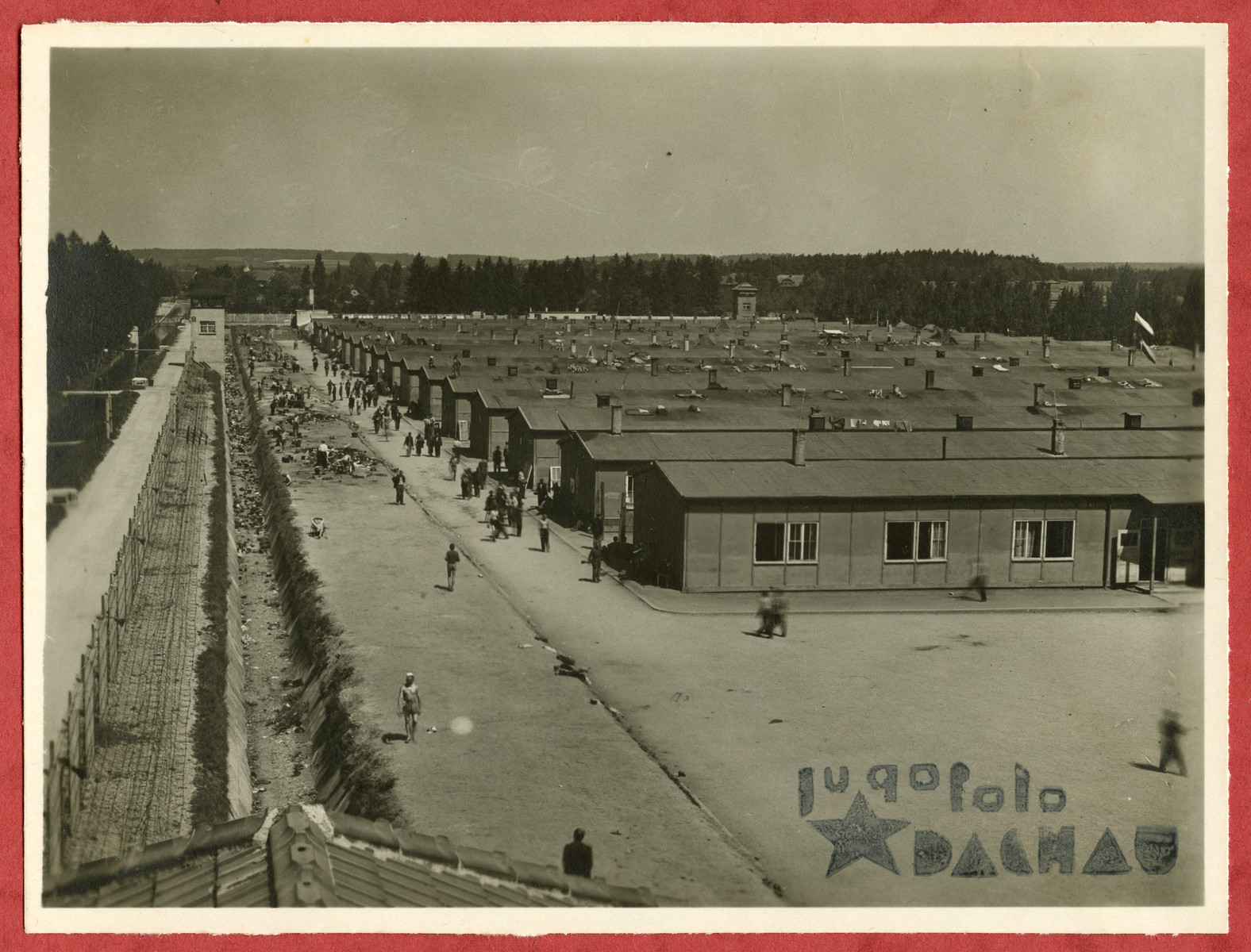 Photograph showing a view of the Dachau concentration camp pasted into an album presented to Lt. Col. Martin Joyce by the Yugoslav prisoner committee.