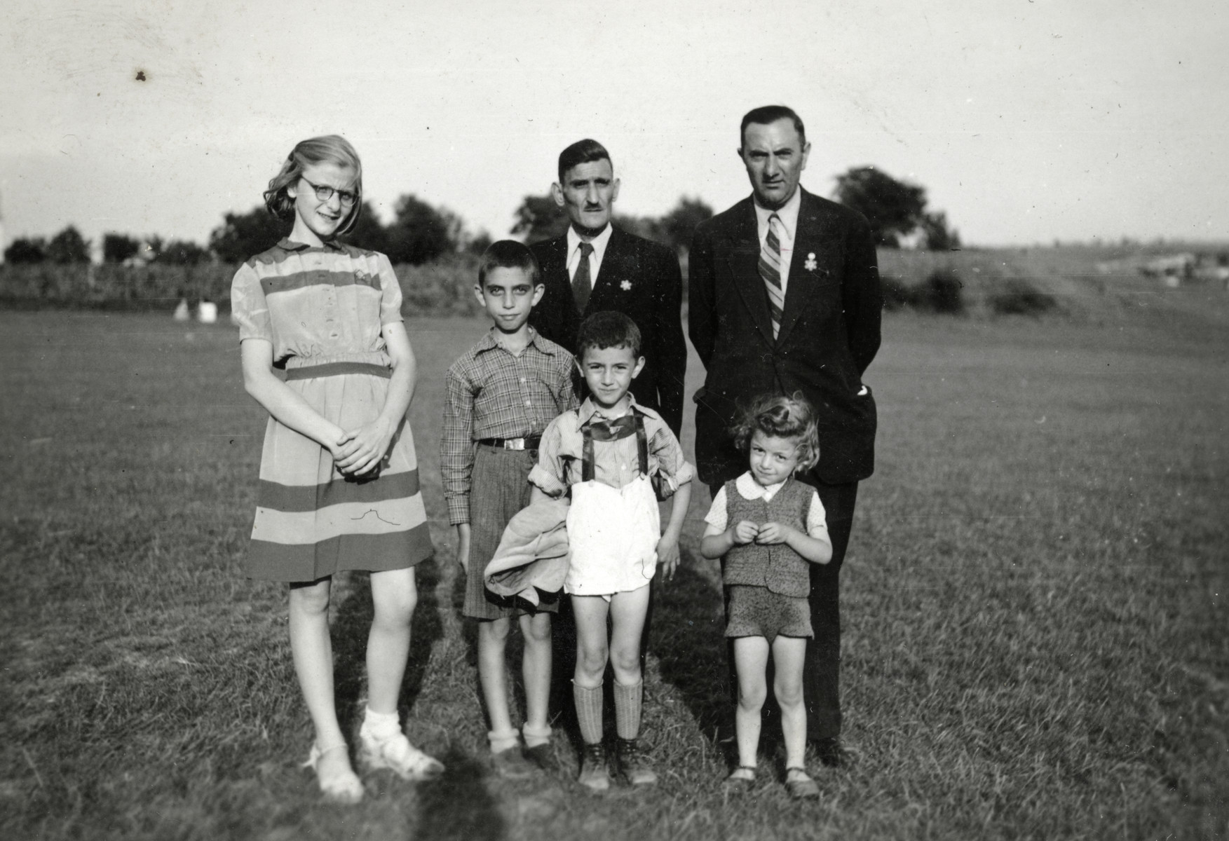 A Jewish family poses in Haskovo where they had been expelled.  The adults are wearing Jewish stars.

From left to right are Reine Behar, her father Rachamin Behar, and Nissim Alvas with his three children.