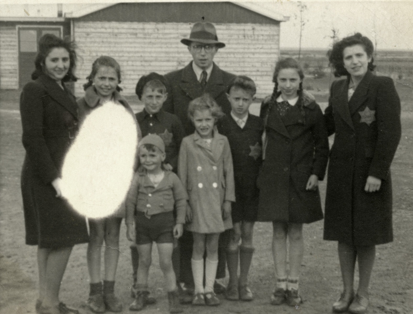 Portrait of the Birnbaum family in the Westerbork transit camp wearing Jewish stars on the street where they lived.

From left to right are an unidentified woman, Regina, Yaakov, Shmuel, Yehoshua, Suzy, Tzvi, Sonni and Regina Ohringer (a first  cousin who perished in Sobibor in 1943 at the age of 16).