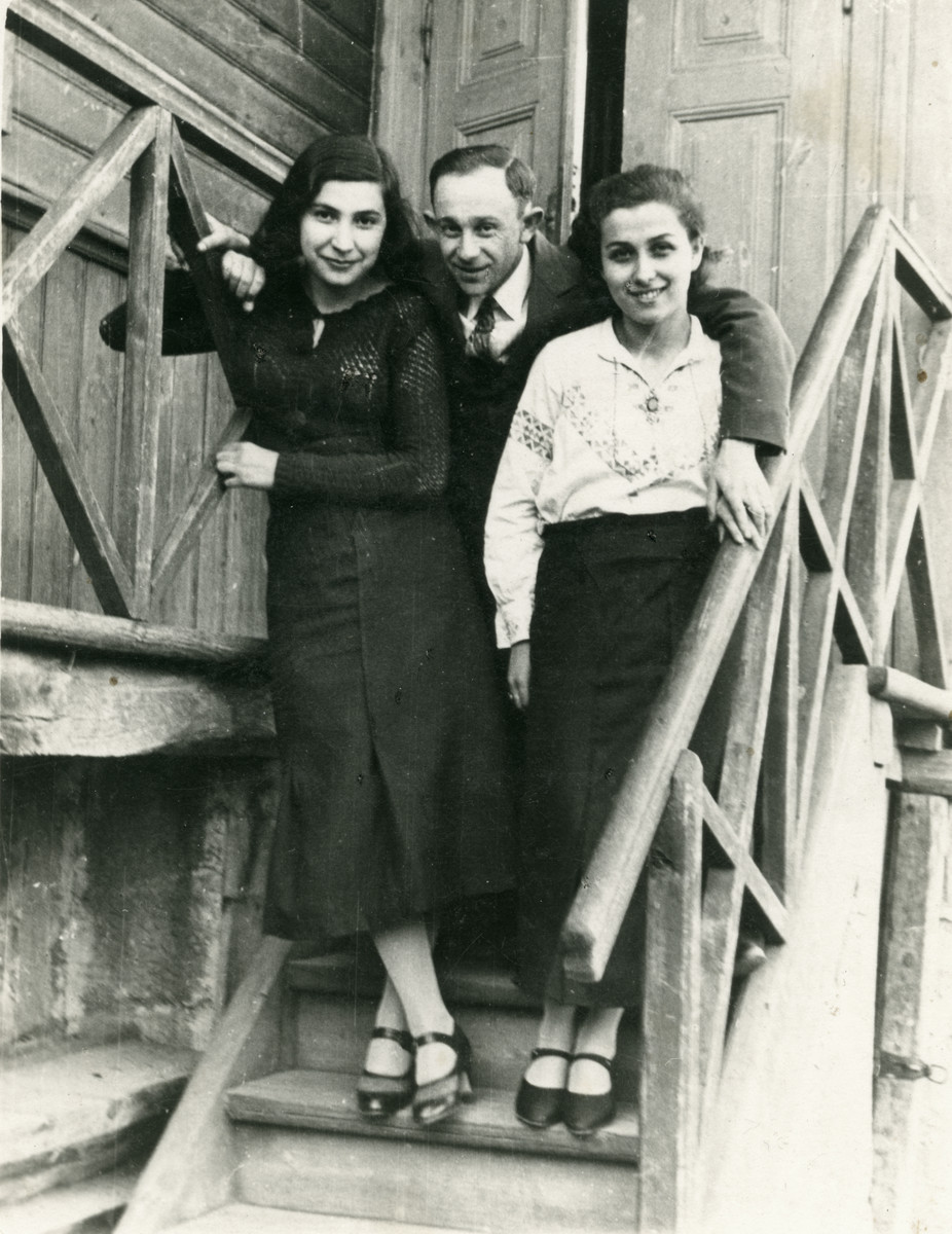 A photo of two women and one man standing on the staircase of a building. 

From left to right Chana Frankfowicz (who later perished in the Holocaust), her brother Feivel Frankfowicz, and his future wife Ethel Rytt.