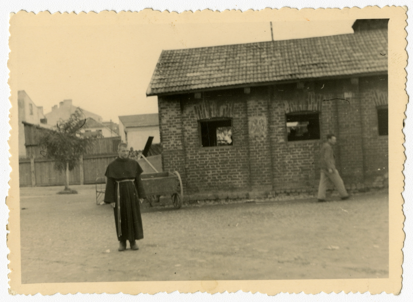 A Polish cleric stands in an open square.

This image is contained in an album found by Jacob Igra in an apartment in Sosnowiec after the war. Many of the photographs are believed to have been taken by a soldier with the SD-SIPO (Sicherheitspolizei) following the invasion of Poland in 1939. Additional photographs depict einsatzgruppen activities at sites throughout Nazi occupied Eastern Europe and may have been later additions to the album.