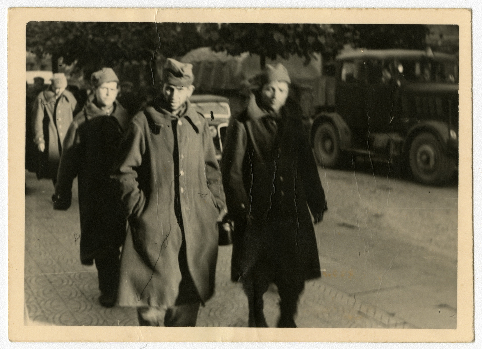 Polish soldiers, likely prisoners of war, walk in the middle of a city street.  

This image is one contained in an album found by Jacob Igra in an apartment in Sosnowiec after the war. Many of the photographs are believed to have been taken by a soldier with the SD-SIPO (Sicherheitspolizei) following the invasion of Poland in 1939. Additional photographs depict einsatzgruppen activities at sites throughout Nazi occupied Eastern Europe and may have been later additions to the album.
