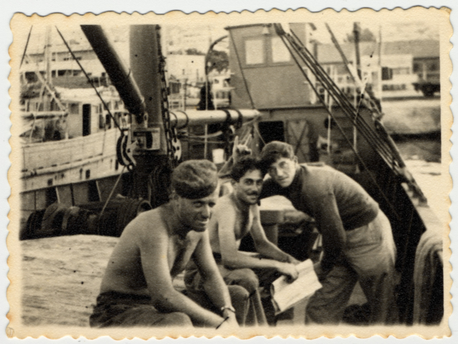 Three crew members of the SS Hannah Szenes relax on a dock in Haifa harbor.

Myron Goldstein is leaning over on the far right.