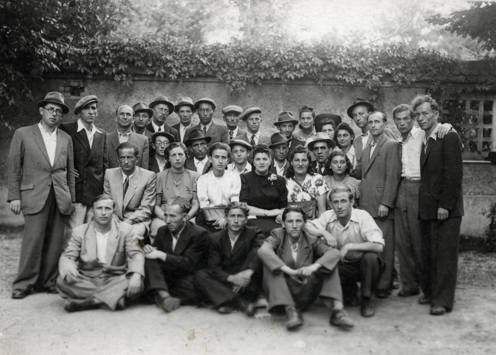 Group portrait of displaced persons in the Eggenfeld DP camp.  

Among those pictured is Zvi Herschel (seated in the back row, second from the right).