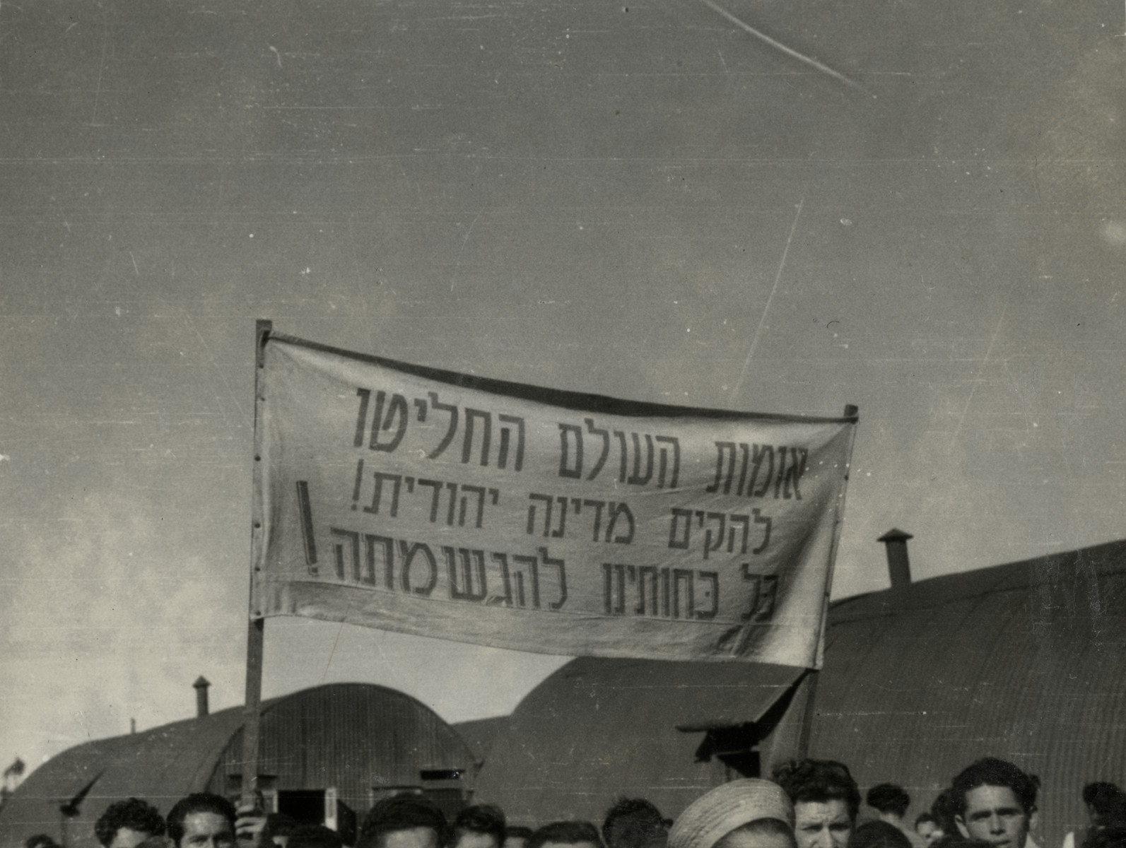 Refugees in Cyprus celebrate the United Nations Partition Plan for Palestine; the sign says that the U.N. decided to create a Jewish state. 

The banner reads "The nations of the world decided to establish a Jewish State.  All our strength is for fulfilling it!"