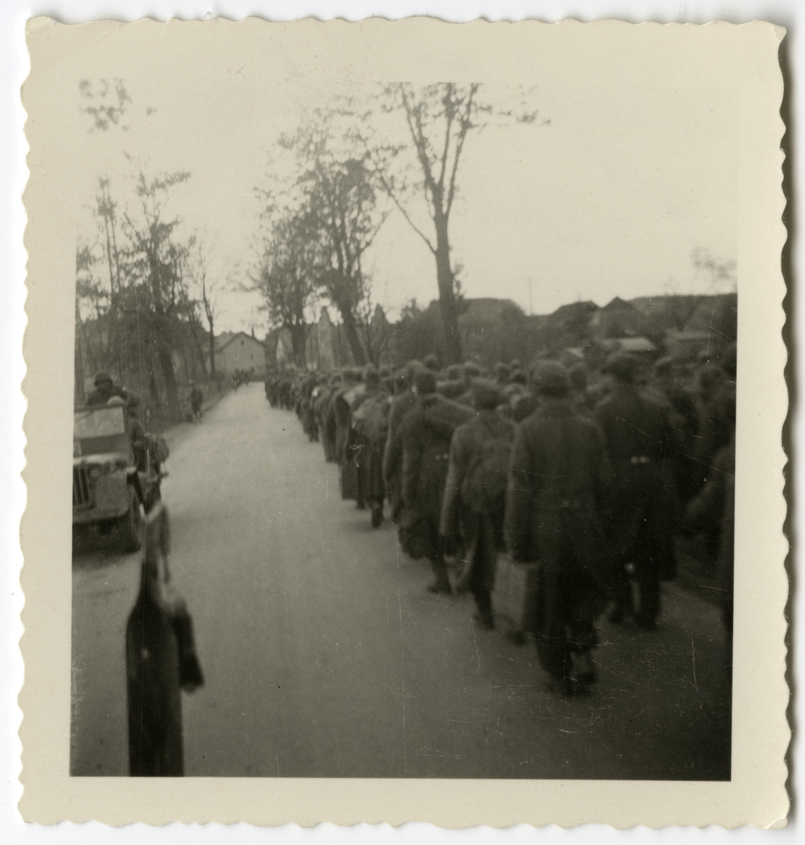 German POWs, captured by the American 261st Regiment, march down the road of an unidentified village.