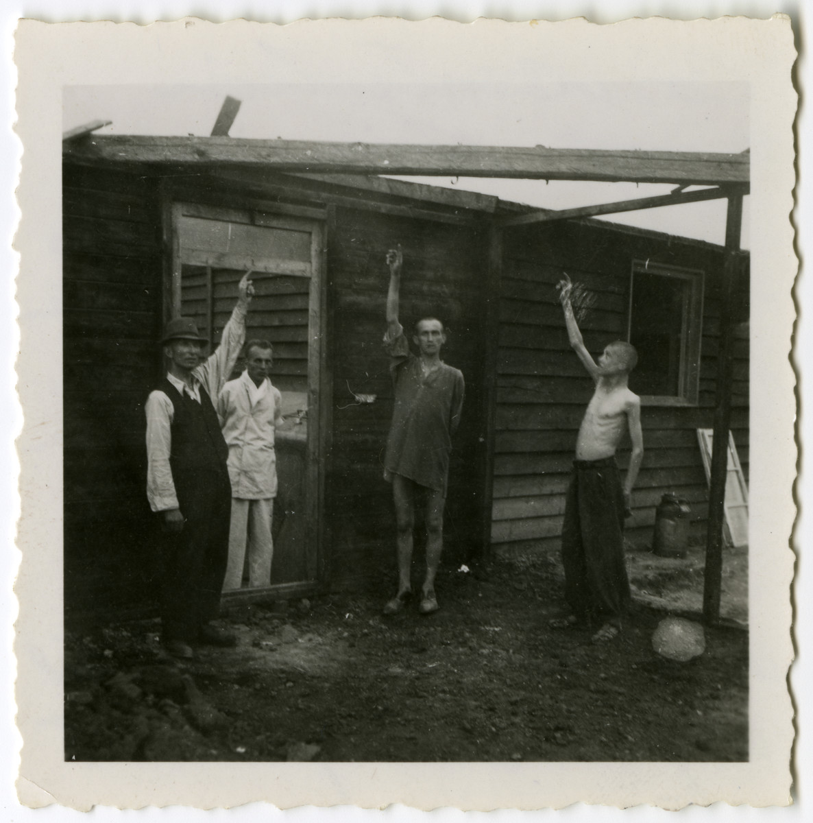 Survivors of Mauthausen [or one its subcamps] demonstrate how the Germans hanged prisoners.

The original caption reads: "Concentration camp. Armies hanged prisoners where men are pointing.  The 2 pointing were to be hanged the next day but were liberated by our regiment."