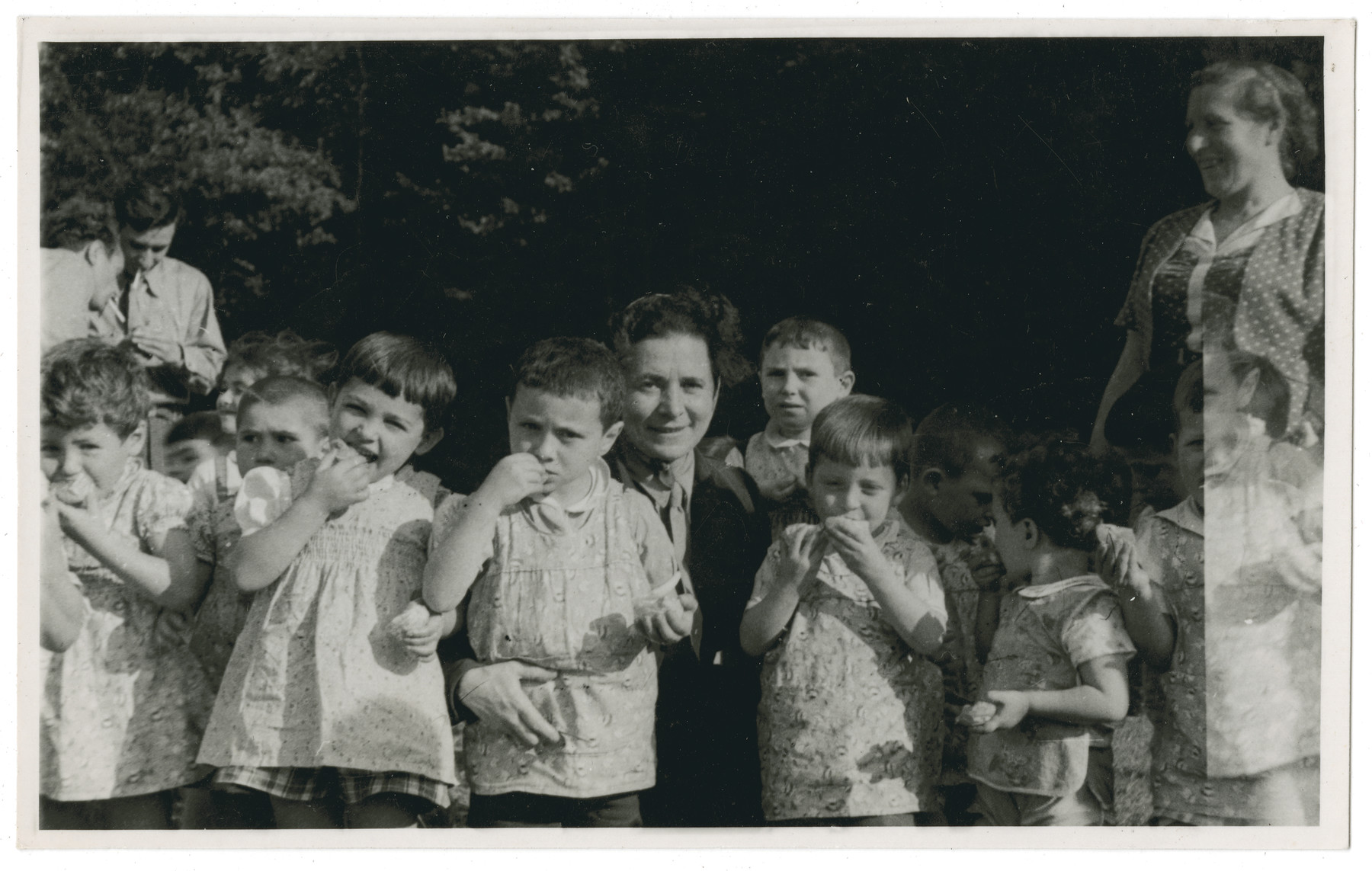 Young children from the Lindenfels home enjoy an outdoor snack.

The original caption reads: "Lindenfels school.  In the woods in the afternoon."