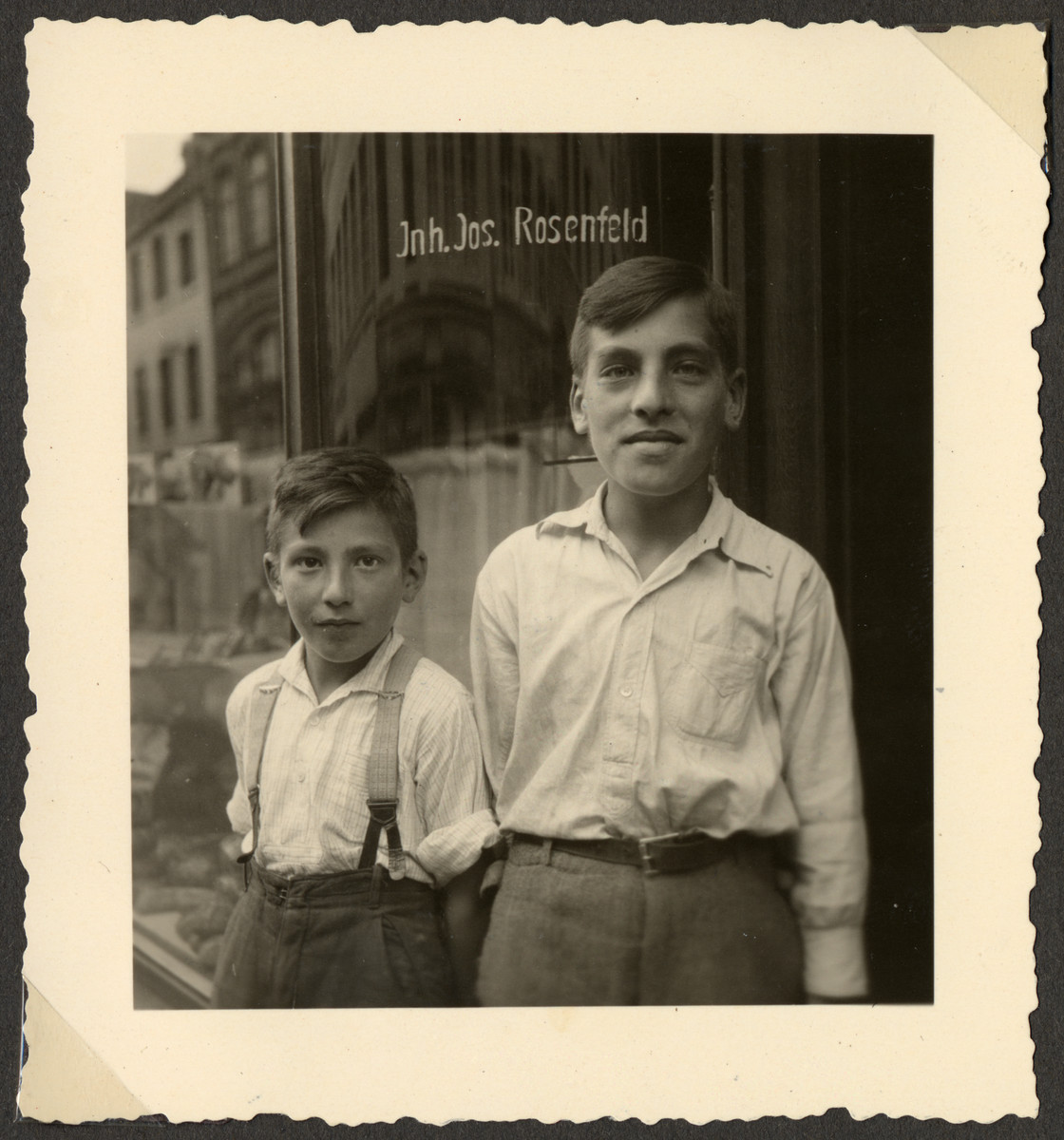 Close-up portrait of two German-Jewish brothers, Hermann (later Heinz) and Willi Rosenfeld, standing in front of their father's bakery at Trier, Neustr. 78.

Hermann and Willi were cousins of the donor of the photograph, and the sons of Josef and Emma Rosenfeld (nee Frank, daughter of Wilhem Frank of Osann/Mosel). Emma died on December 14, 1931 and Josef married Marta Kalbermann (b. December 7, 1901).