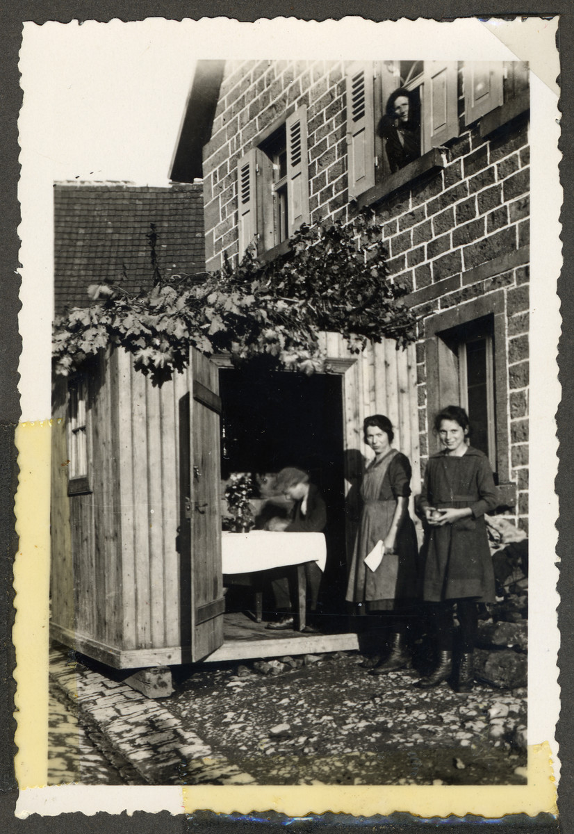 Two women from the Kalberman family stand outside their sukkah belonging to Emanuel and Rosa Kalbermann.

Standing on the left is Marta Rosenfeld Kalbermann.