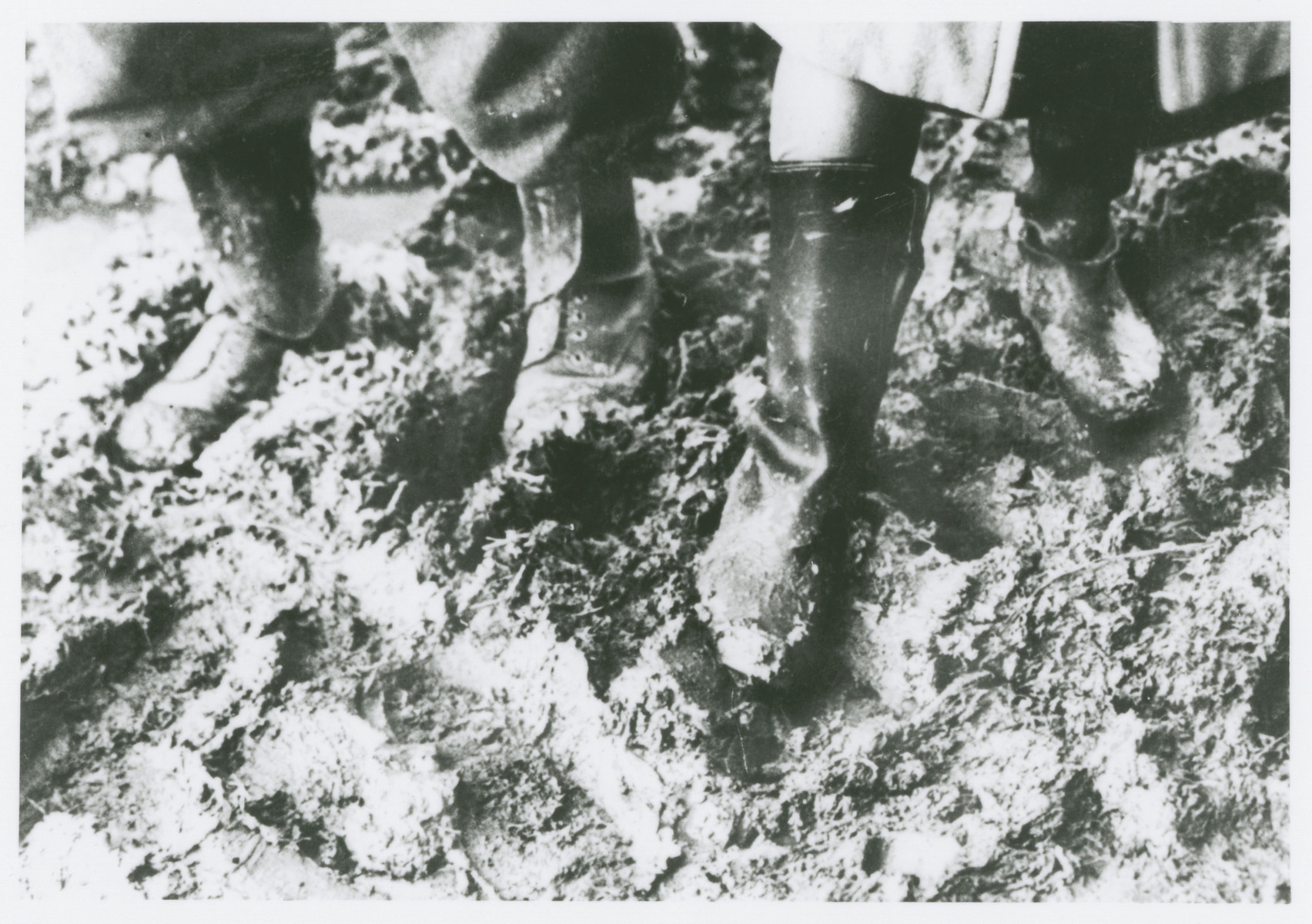 Close-up of the feet of two prisoners walking through the mud at the Novaky labor camp.