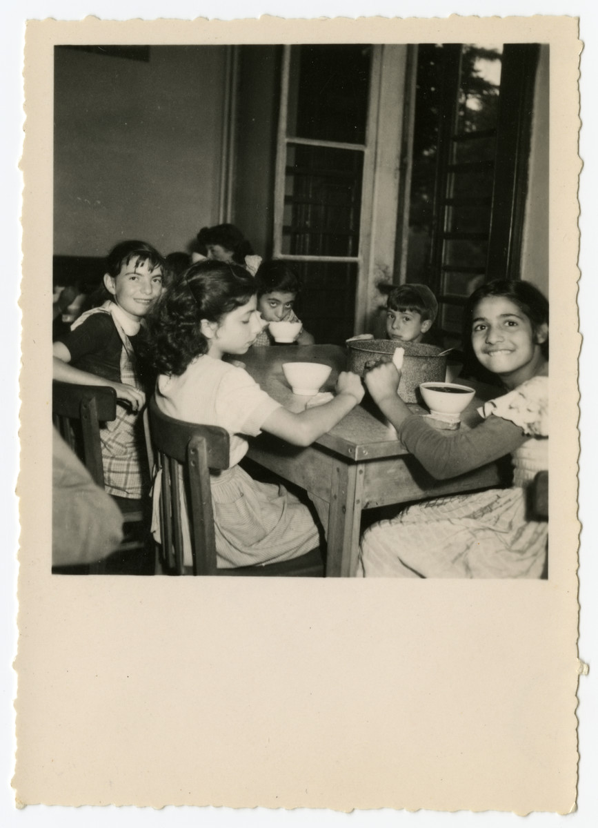 Children eat a meal in the  OSE Taverny children's home.

Beate Zimmern is facing the camera on the left behind Francine.  Edmee is sipping her soup to the left of my sister. The counselor Helene Ekayser Weksler is seated in the back, partially obscured.