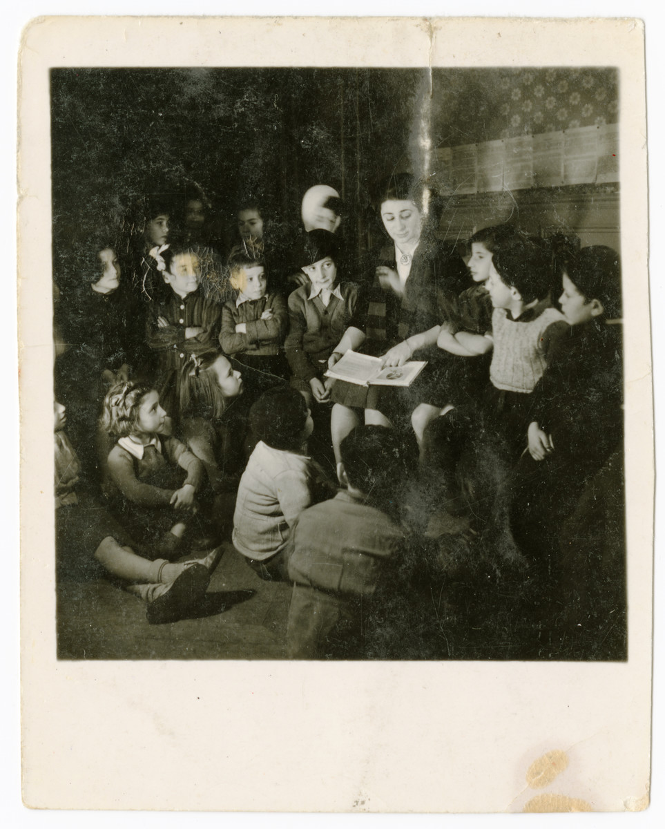 A woman reads aloud to a group of children in the OSE Taverny children's home..