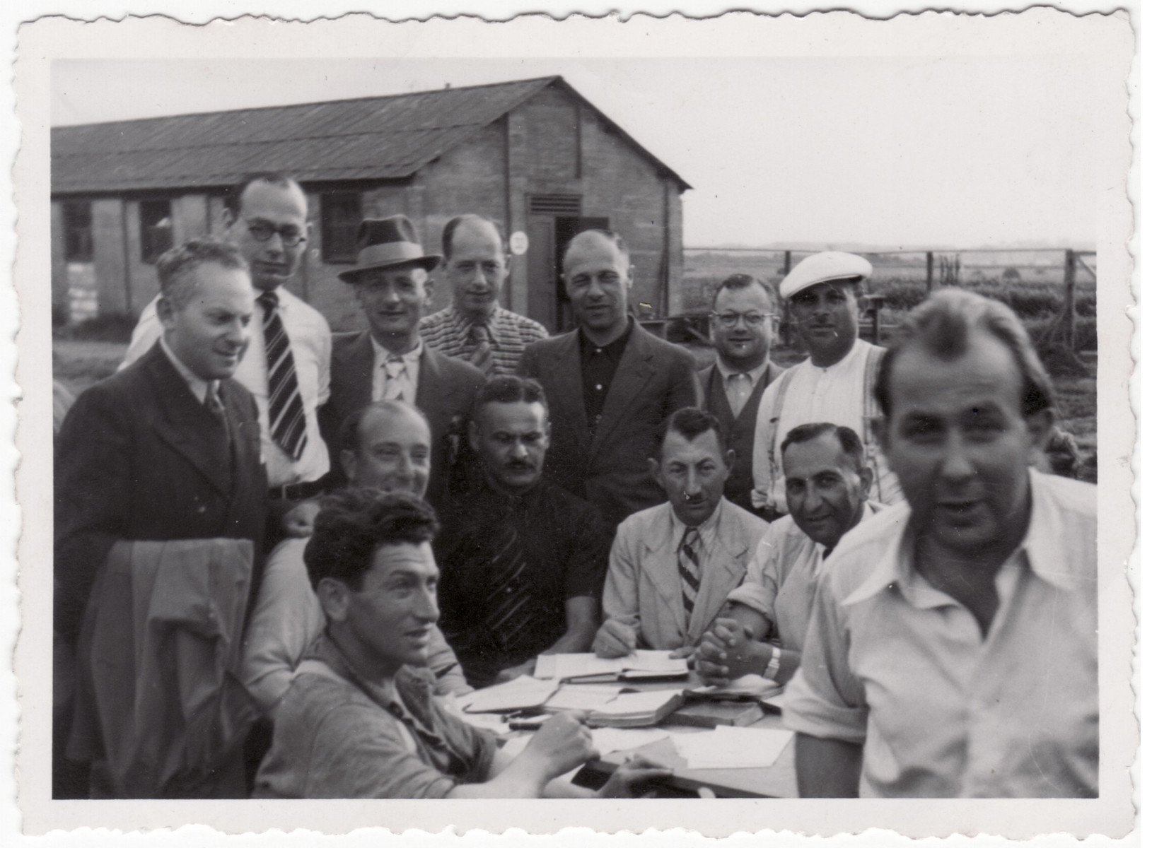 Jewish men gather around an outdoor table in the Kitchener refugee camp.

Siegfried Kulmann is pictured in the lower right wearing a white short sleeve shirt.
