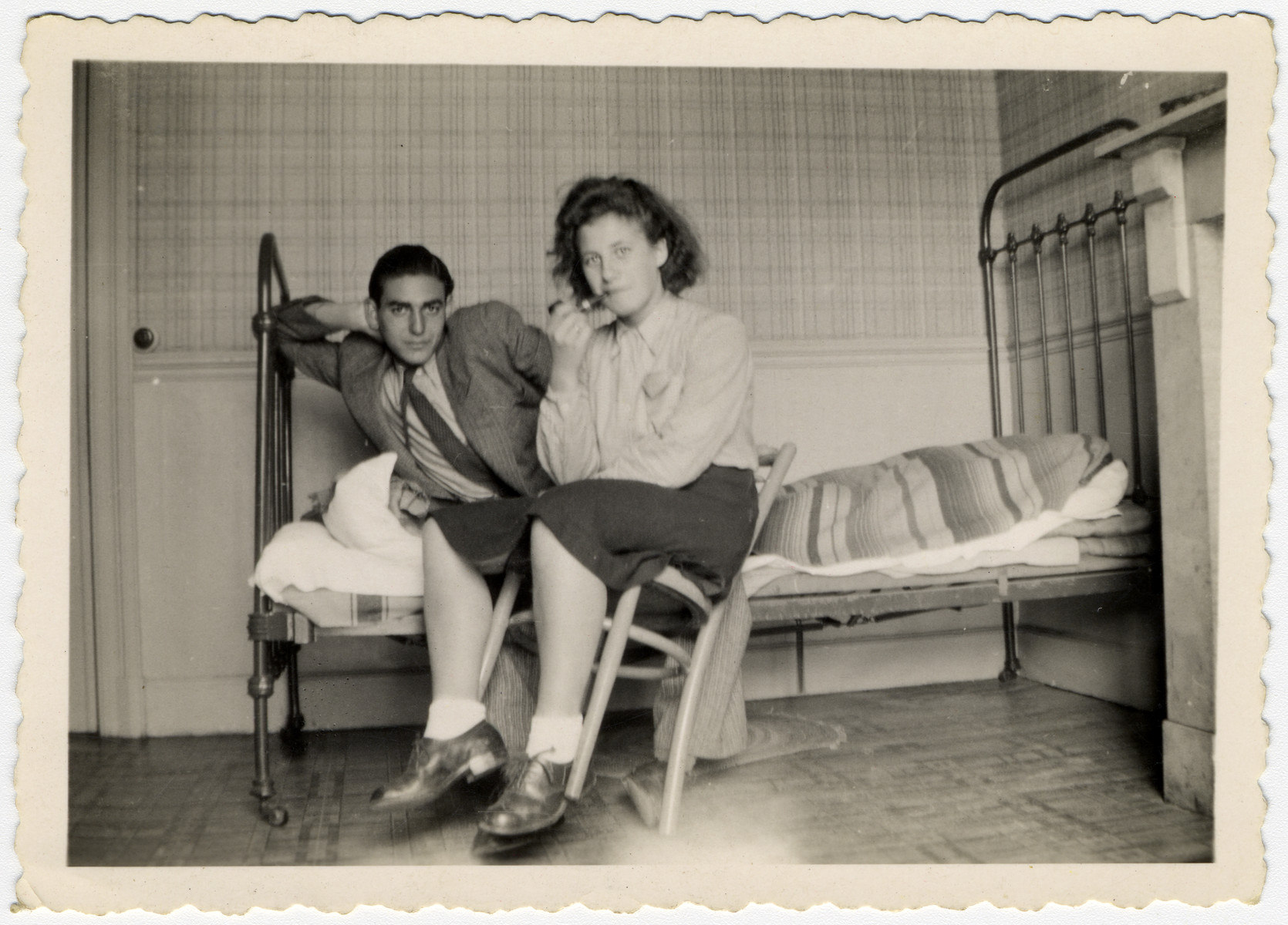 Two Jewish young people pose in a room with a bed and chair.

Pictured are Haim Vidal Sephiha and Ida (Naomi) Rosenschtraugh.  She later immigrated to Israel.