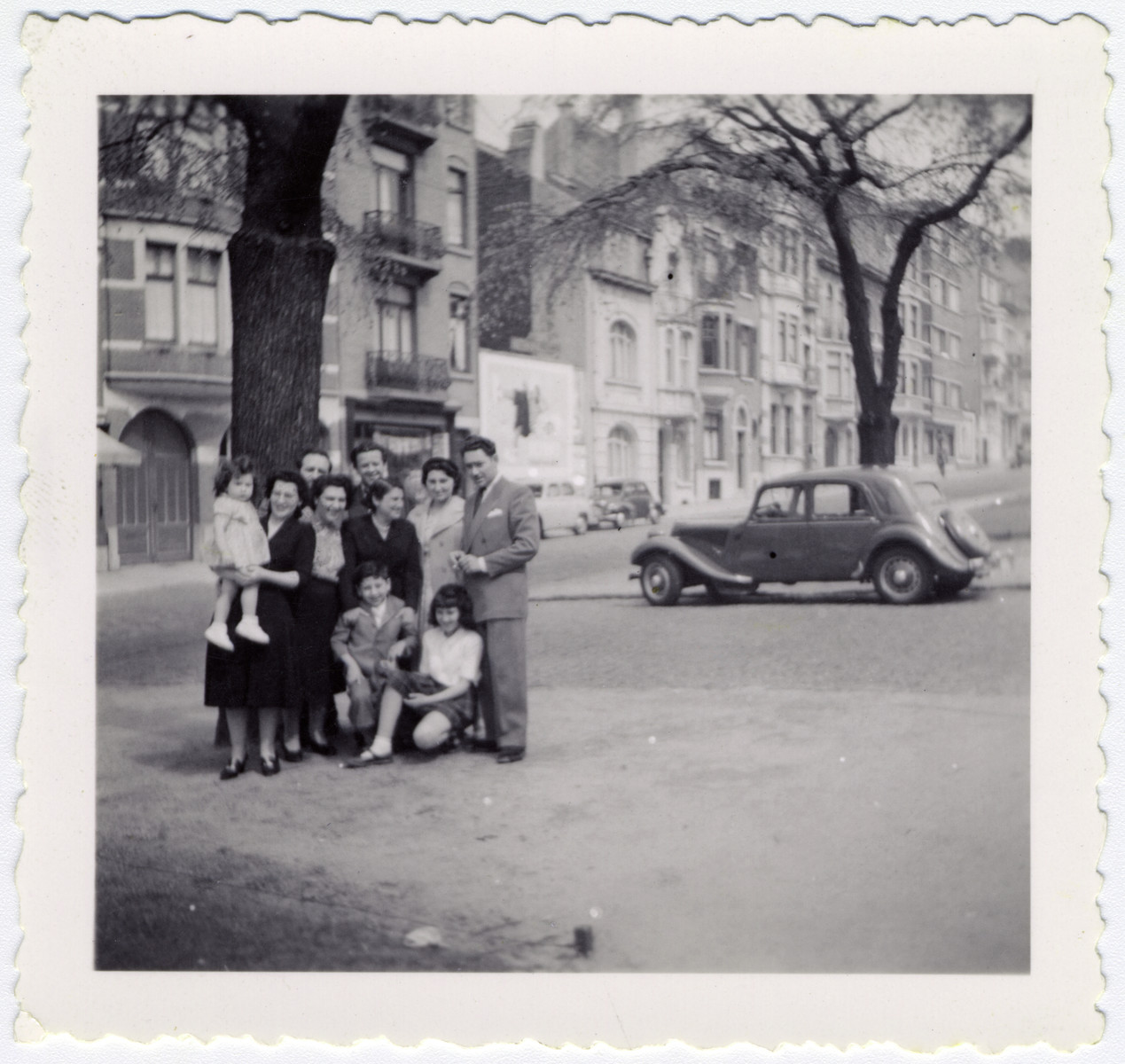 Postwar family photograph of the Sephiha family standing on a sidewalk in Brussels.

On the left is Germaine Sephiha holding Claudine Ariel, Adele Sephia Ascagno, Jacqueline Wolff, Elise Ariel, and Albert Sephia.  In front are Raymond and Monique Ariel, and in back are Elie Ariel and Guelfi Ascagno.