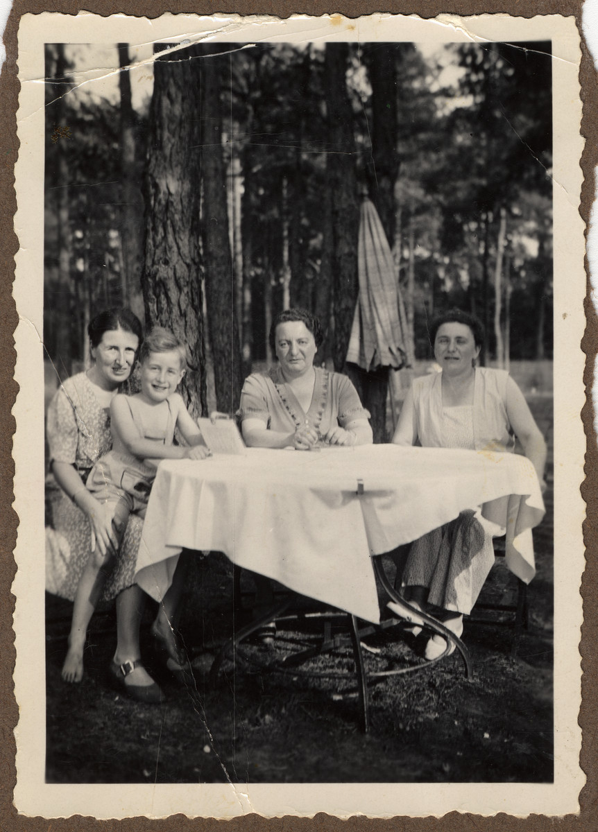 Three women gather at an outdoor table.

From left to right are Ilse Baruch holding her son Peter, her sisters-in-law Thekla Erdman and Marianne Ziegler.  Ilse and Peter survived, but Thekla Erdmana nd Marianne Ziegler perished in the Holocaust.