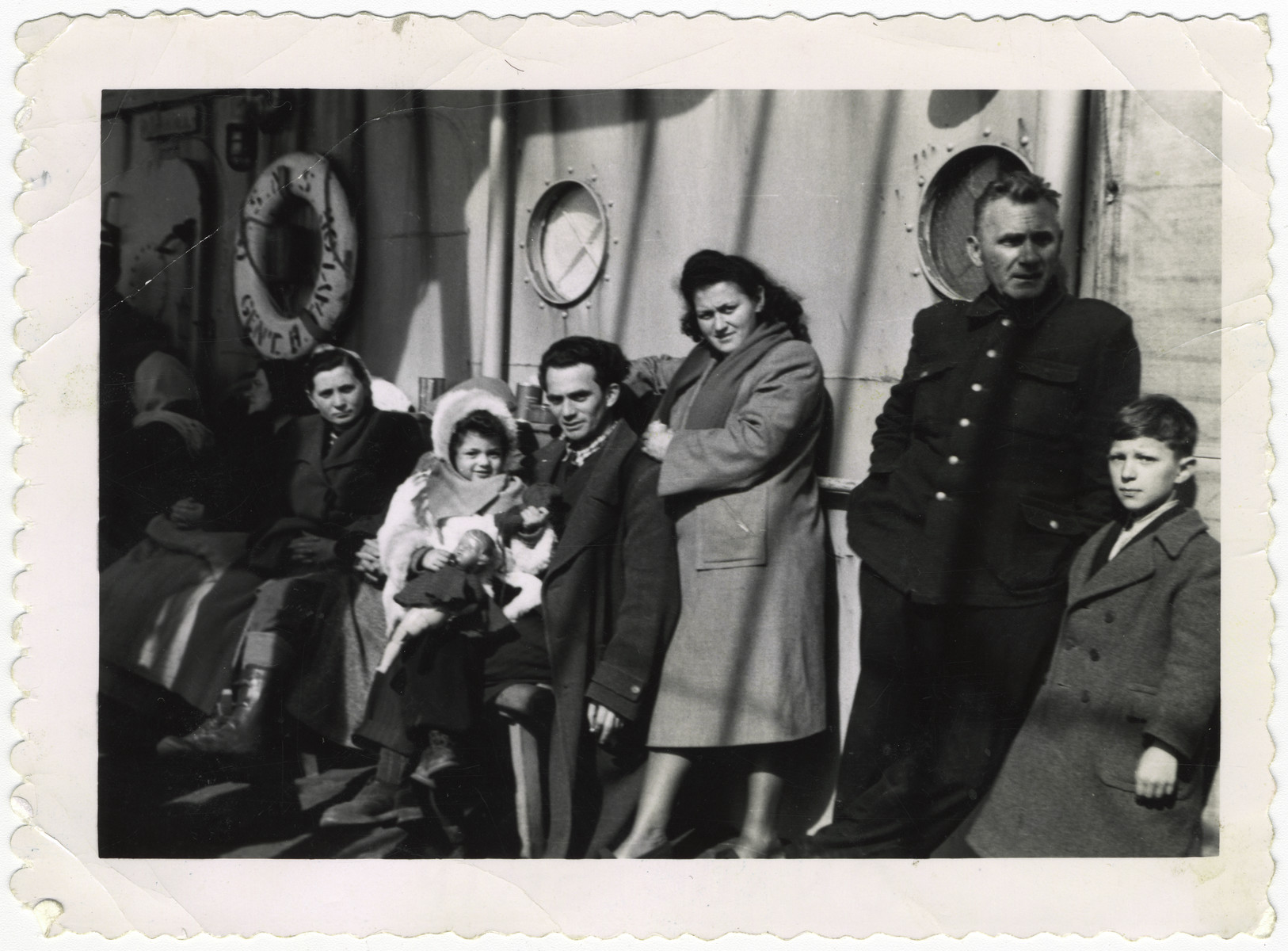 A Jewish family on board the ship "Henry Taylor," enroute to the United States.  

Pictured in the center is  Regina Zawierucha (later Zavier), holding her doll; to her left are her father, Sender, and her mother, Pola.