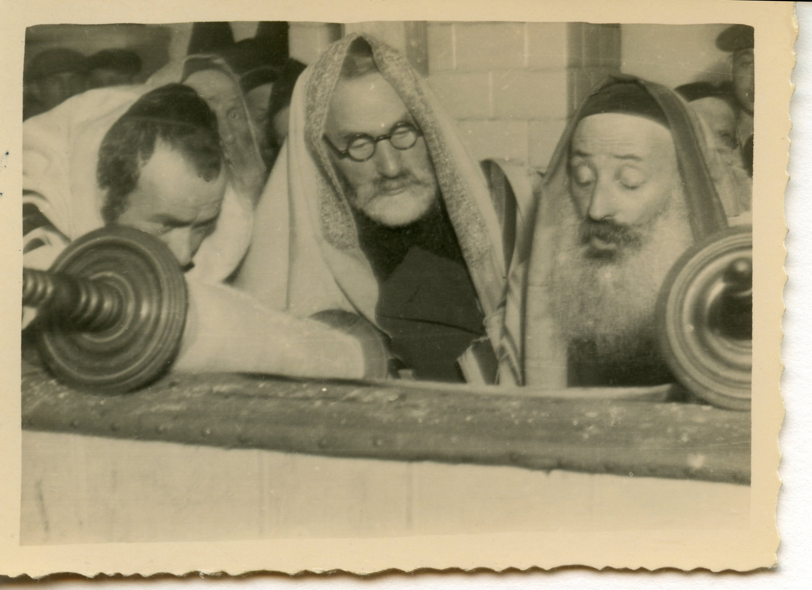 Three men read from a Torah scroll [perhaps in Osieciny].