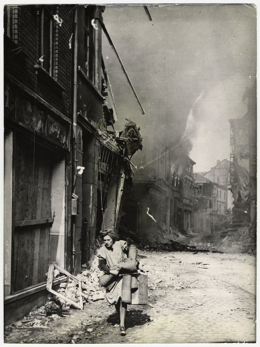 A German woman flees a burning area in Sieburg.  

The original caption reads: "As a fire rages in the background, a German woman carries her belongings from a burning building on newly captured Sieburg, five mile northeast of Bonn and the Rhine, on the south of the Ruhr pockets. U,S, Signal Corps Photo."