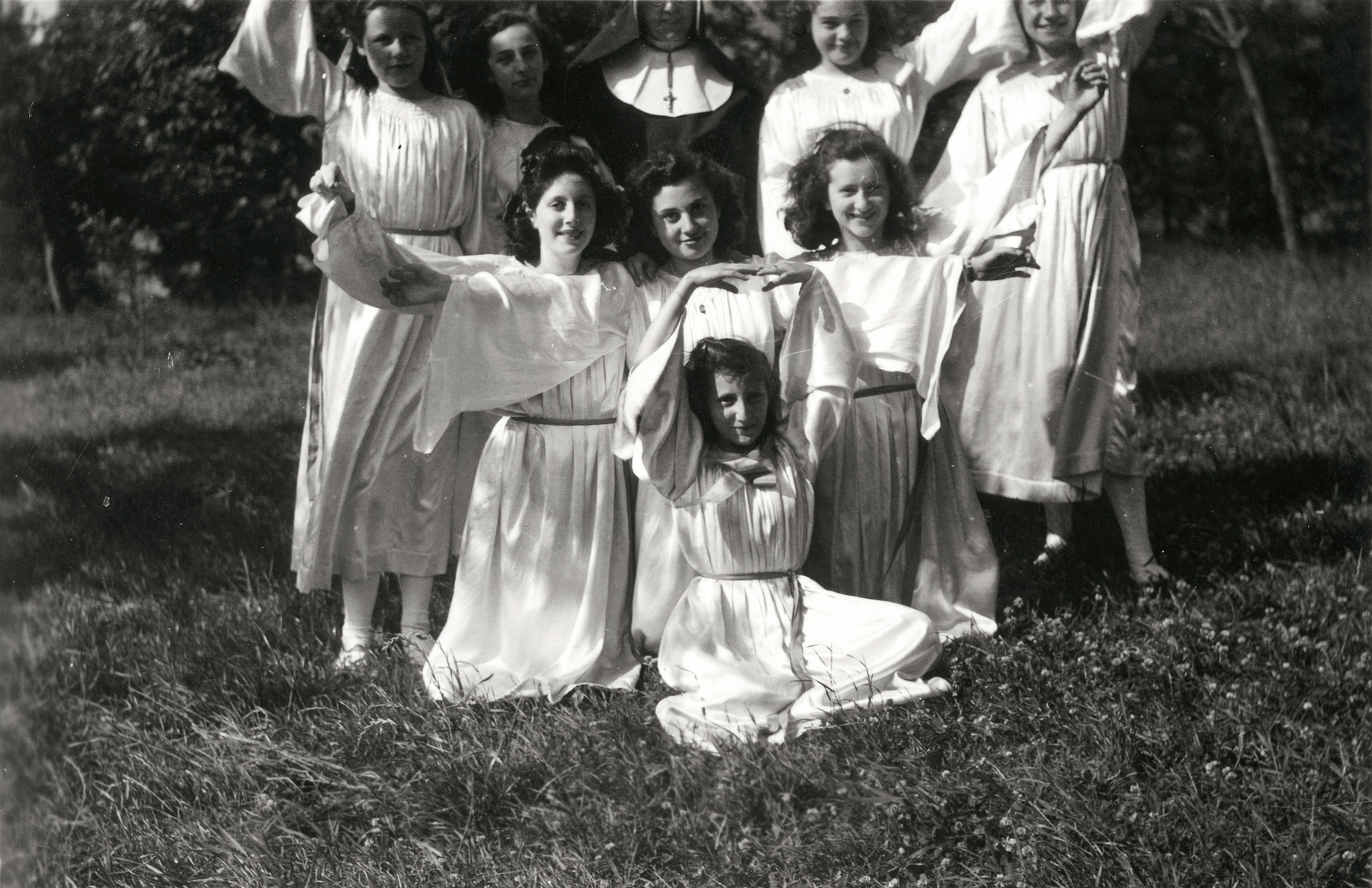 Group portrait of school girls, including Jewish girls in hiding, in the St. Antoine de Padue convent.

Liliane Ferdman is pictured in front with her hands above her head.