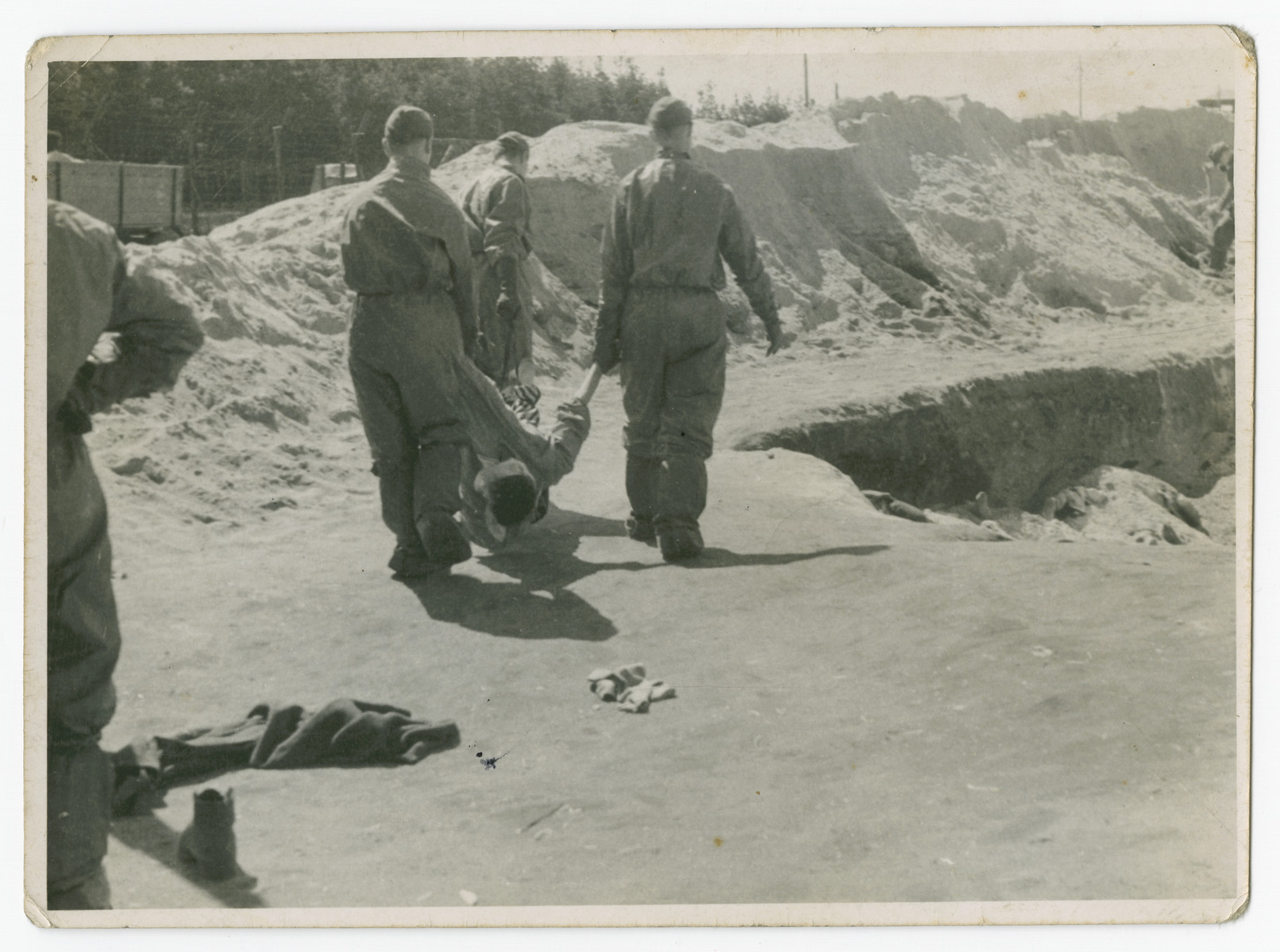 Soldiers bury victims in a large pit in the Bergen-Belsen concentration camp following liberation.

The original caption reads: "From truck to pit at Belsen."