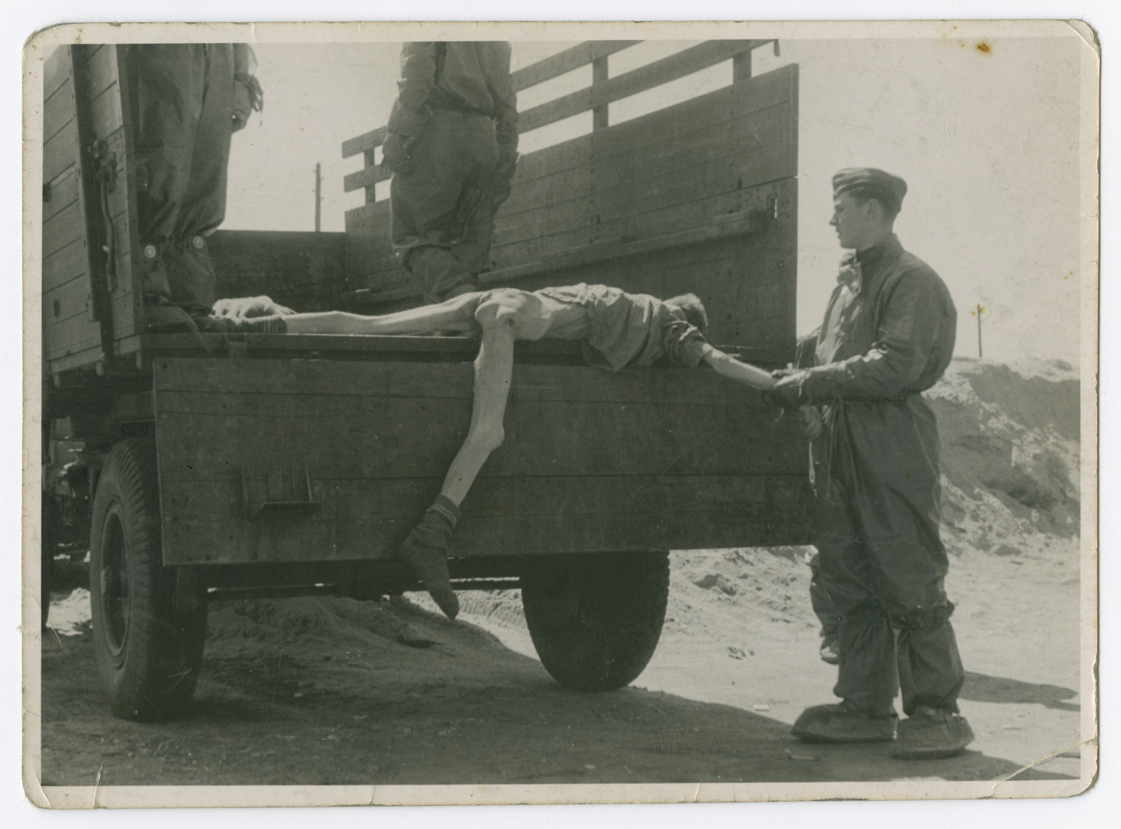 Soldiers load corpses onto trucks prior to the their burial.

The original caption reads: "Loading another bunch of stiffs in the truck for the pit in Bensen."