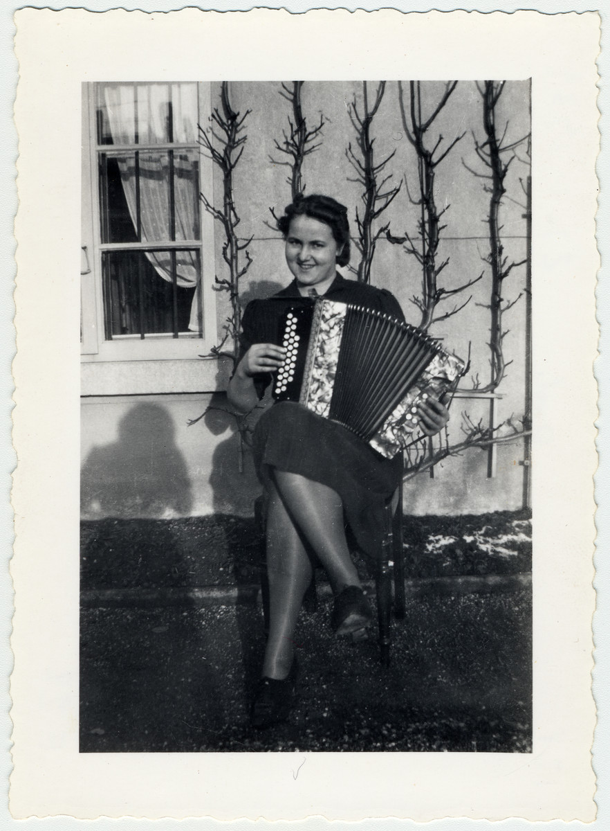 Gret Luley sits outside a building in the Herzog's garden playing the accordion.