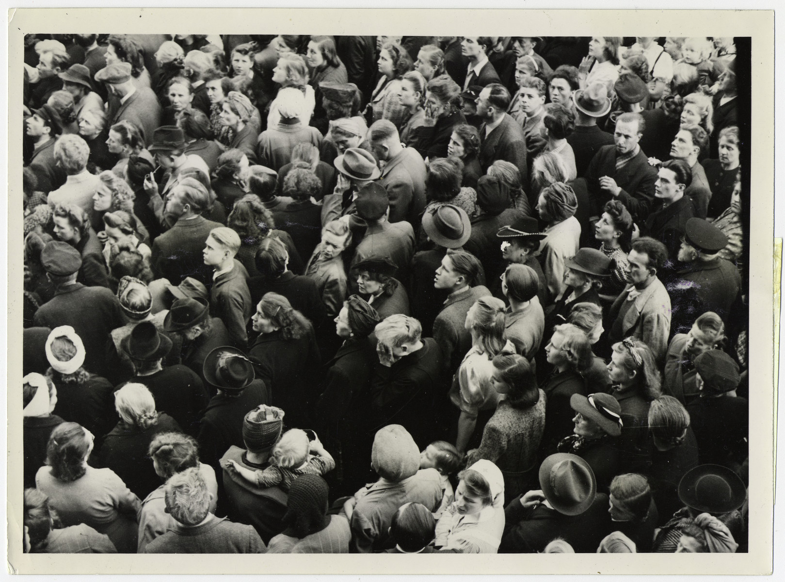 Official British photograph showing German civilians listening to the terms of German surrender. 

Original caption reads, "Thousands of German civilians gathered in the square in front of the ancient Town Hall at Lueneburg to hear the official news of the surrender of all the German armed forces in Europe. A British loud speaker van was used to relay the news in German.  An old woman in centre of crowded square weeps as she hears the news."