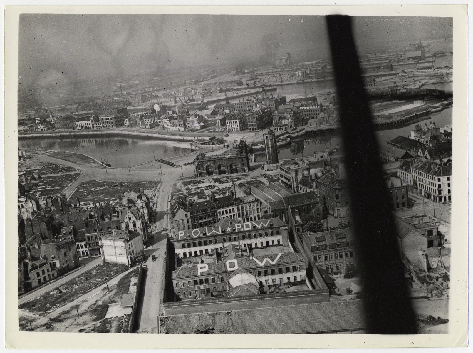 British official aerial photograph of Dunkirk.

Original caption reads: "An R.A.F official photographer flew over Dunkirk on 11.5.45 and took these air views of one of the last of the surrendering German outposts.
Picture shows:- General view over the town of Dunkirk showing prisoner of war signs painted on the roofs of buildings."