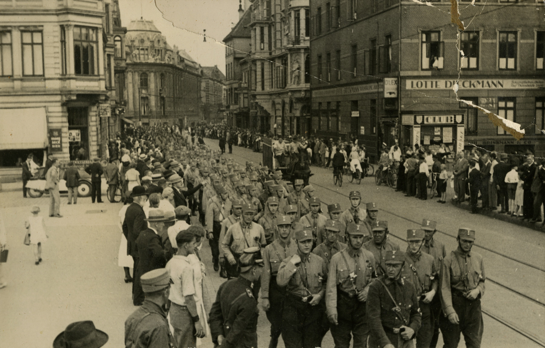 Street view of Nazi soldiers marching through the streets of Bremen, Germany in 1932.

Original caption on album page reads, "1932 Germany." Bottom-most photo caption reads, "A gathering of Hitler supporters in Hamburg before election in 1932." Top photo caption reads "Hitler Soldiers marching the street at Bremen; Irving and I saw their parade."