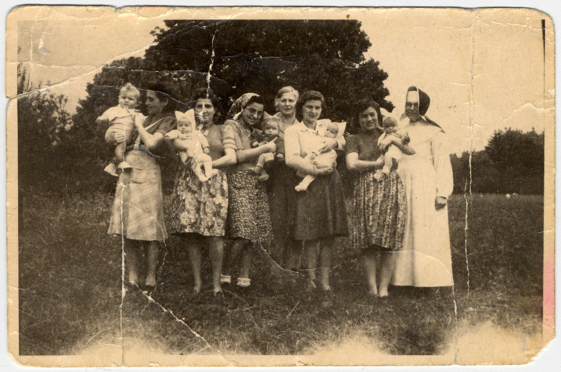 Group portrait of five Hungarian Jewish mothers with their infants at the Saint Ottilien sanitorium in Germany.   All were part of the Schwanger Kommando in the Kaufering concentration camp. 

Pictured from left to right are:  Elizabeth (Boezsi) Legmann with her son Gyuri, Ibolya Kovacs with her daughter Agnes; Suri Hirsch with her son Yossi;  Magda Fenyvesi's mother, Magda Fenyvesi with her daughter Judit; and Dora Loewy with her daughter Zsuzsi.  

Not pictured are: Eva Fleishmanova and her daughter Maria; and Miriam Schwarcz Rosenthal and her son Laci (Leslie).
