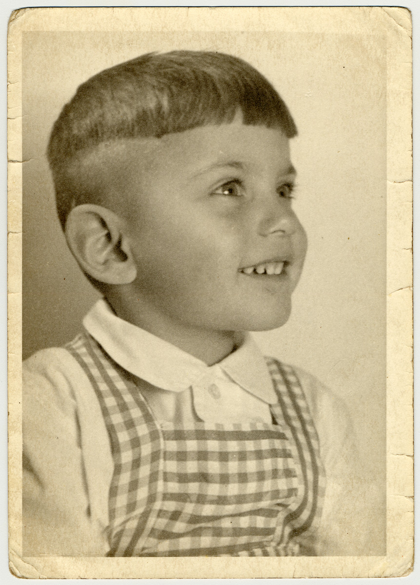 Studio portrait of a young boy in a plaid jumper.  Pictured is Uri Hanauer, a year before his deportation to Theresienstadt.