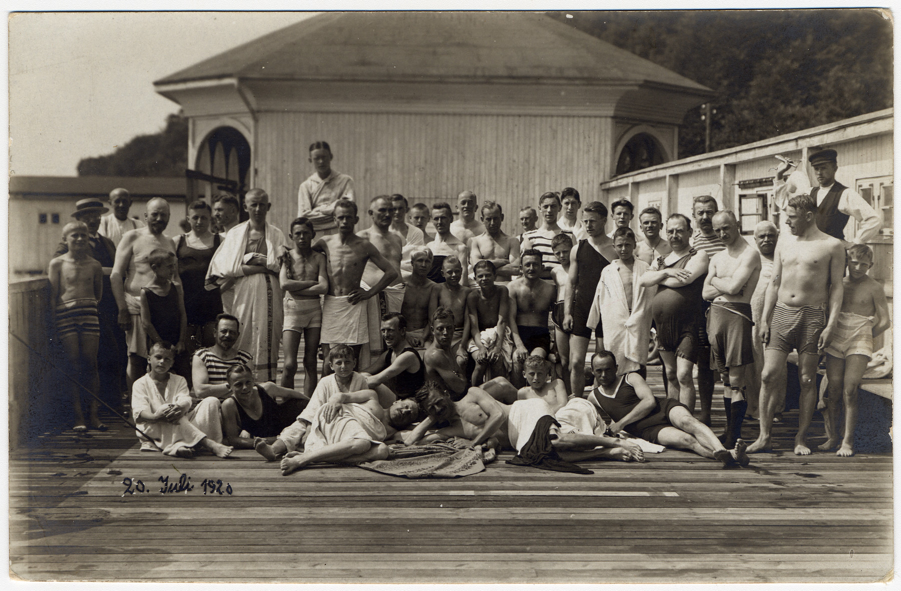 Max Hanauer sits in the center wearing black swimming trunks.