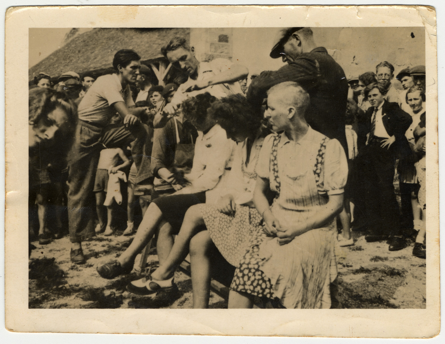 Women accused of collaborating with the Nazis are publicly humiliated by having their heads forcibly shaved after the war in either France or Belgium.

Note: Similar displays took place in both France and Belgium and there is no original documentation indicating where this photo was taken.