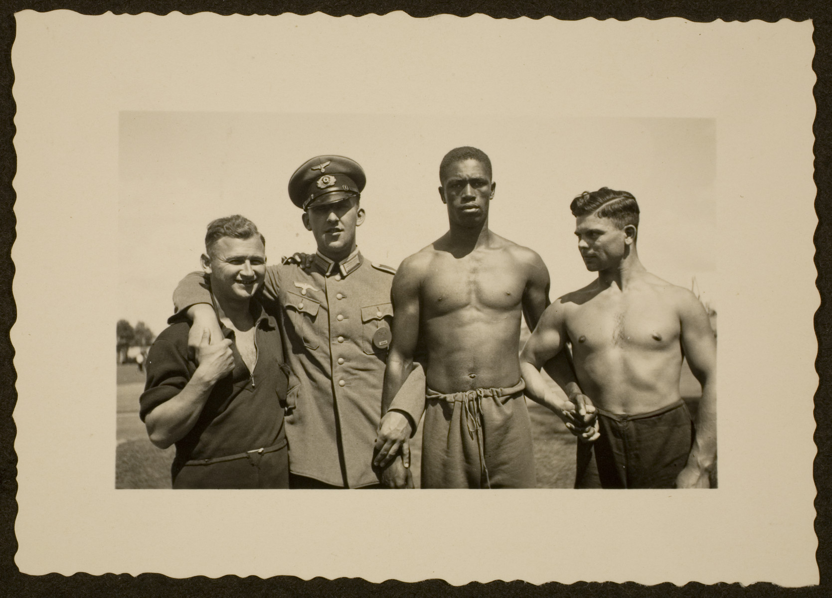 A German in an Army uniform poses with Olympic athletes.

Pictured second from the right is American track and field athlete John Woodruff.  Fritz Bezzelt (father of the donor) is pictured on the far right.