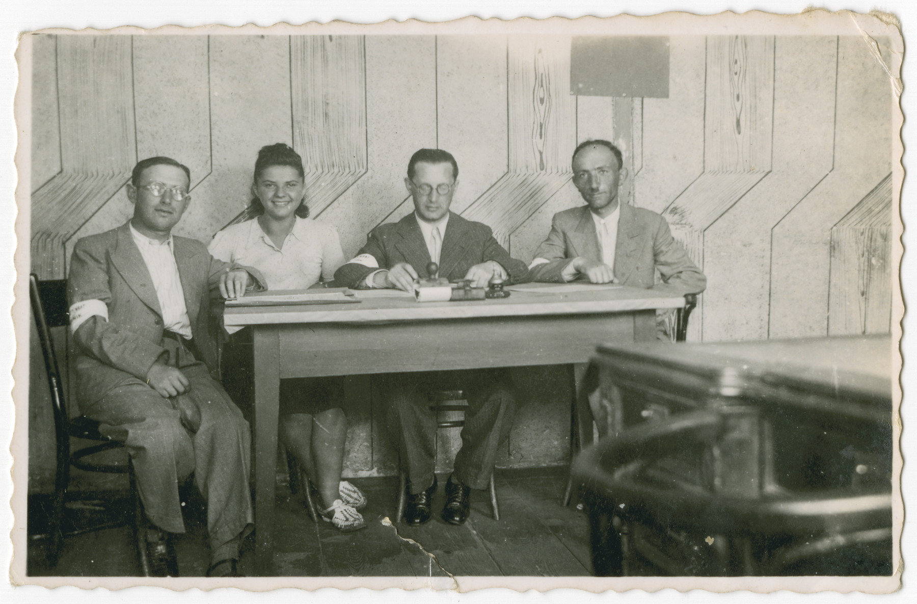 Members of the Jewish Council in Chmielnik seated at a table. 

Pictured from left to right are "Scyzoryk," Bluma Kleinhandler, Abram Langwald (president), and Chaim Dab (Domb, secretary).