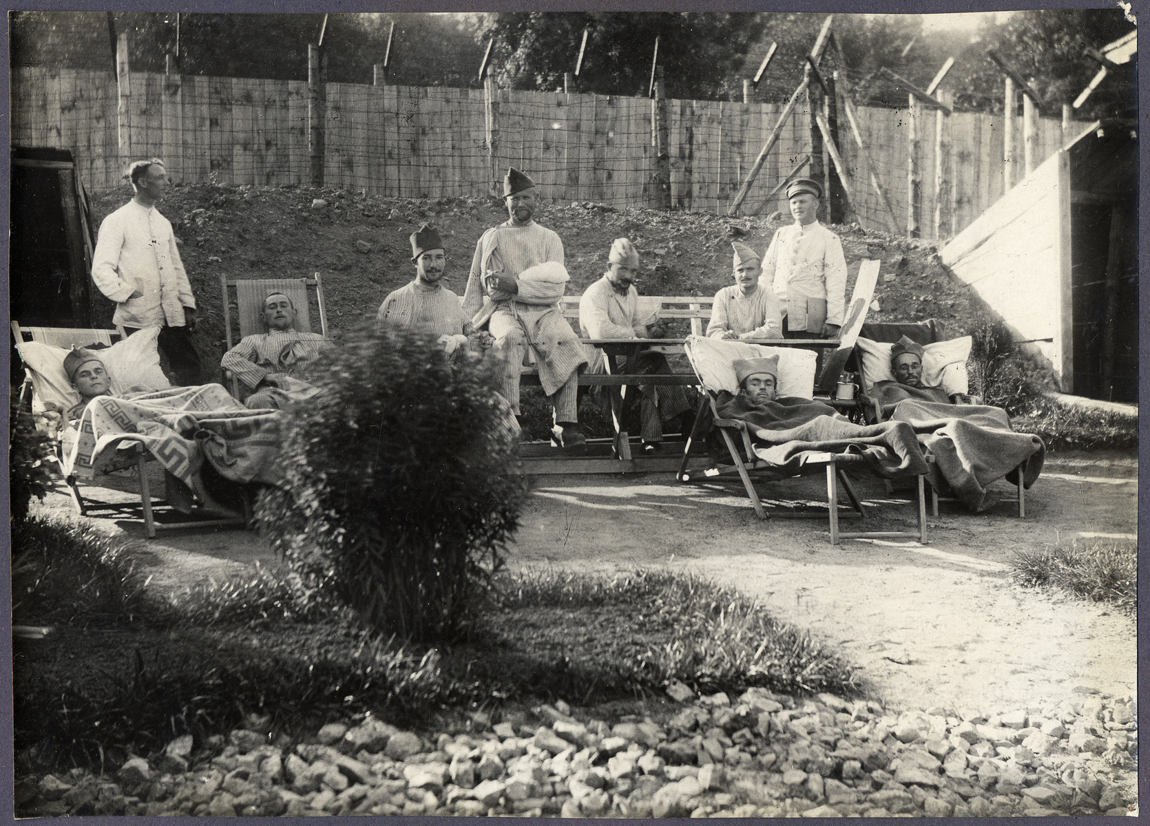 World War I POWs, many in French Army caps, relax outside in a military hospital at a prisoner of war camp.