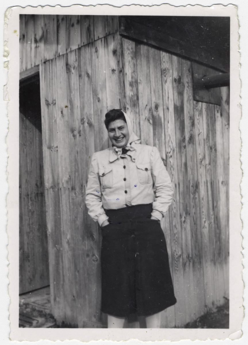 Ruth Lambert poses in front of a wooden building at the Gurs internment camp in France. 

Original caption reads: "Ruth Lambert, Gurs Camp, December 1942."