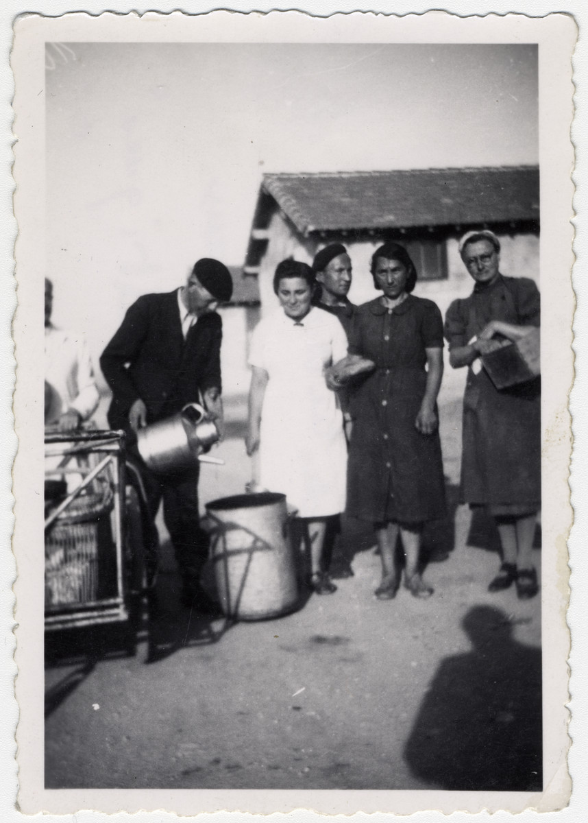 Women wait in line to be served in the Rivesaltes internment camp. 

Original caption reads: "The distribution of food to the cachetic, O.S.E."

(The caption refers to an illness, cachexia, which is associated with malnourishment, weight and muscle loss in someone who is not actively trying to lose weight.)