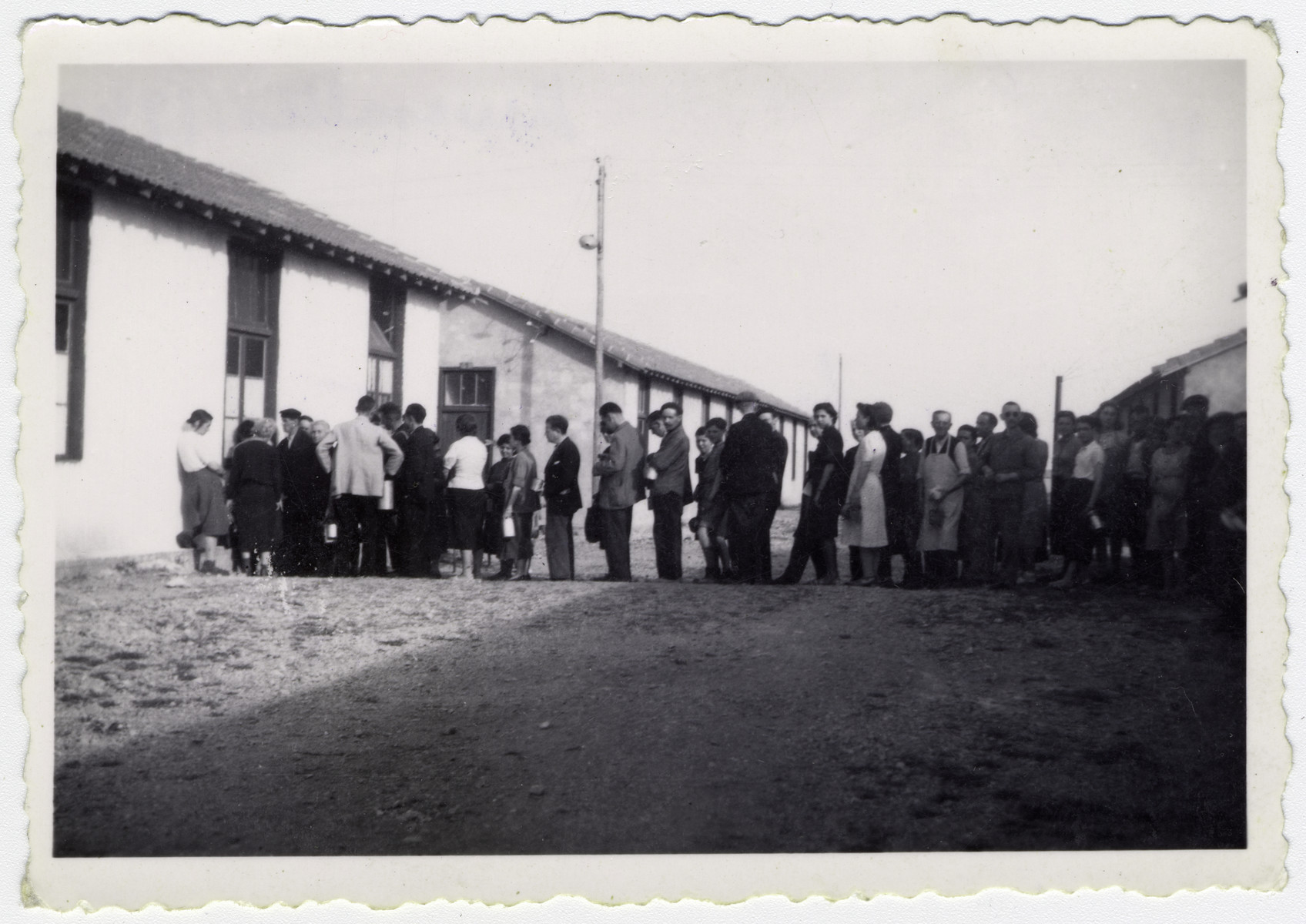 A line of prisoners wait to be served their rations at the Rivesaltes internment camp. 

Original caption reads: "The line for soup."