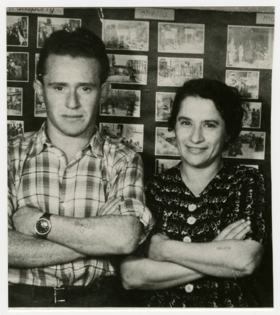 Bronislaw Gelczynski (Abraham Gordon) and an unidentified woman pose in front of a display of Holocaust photographs.