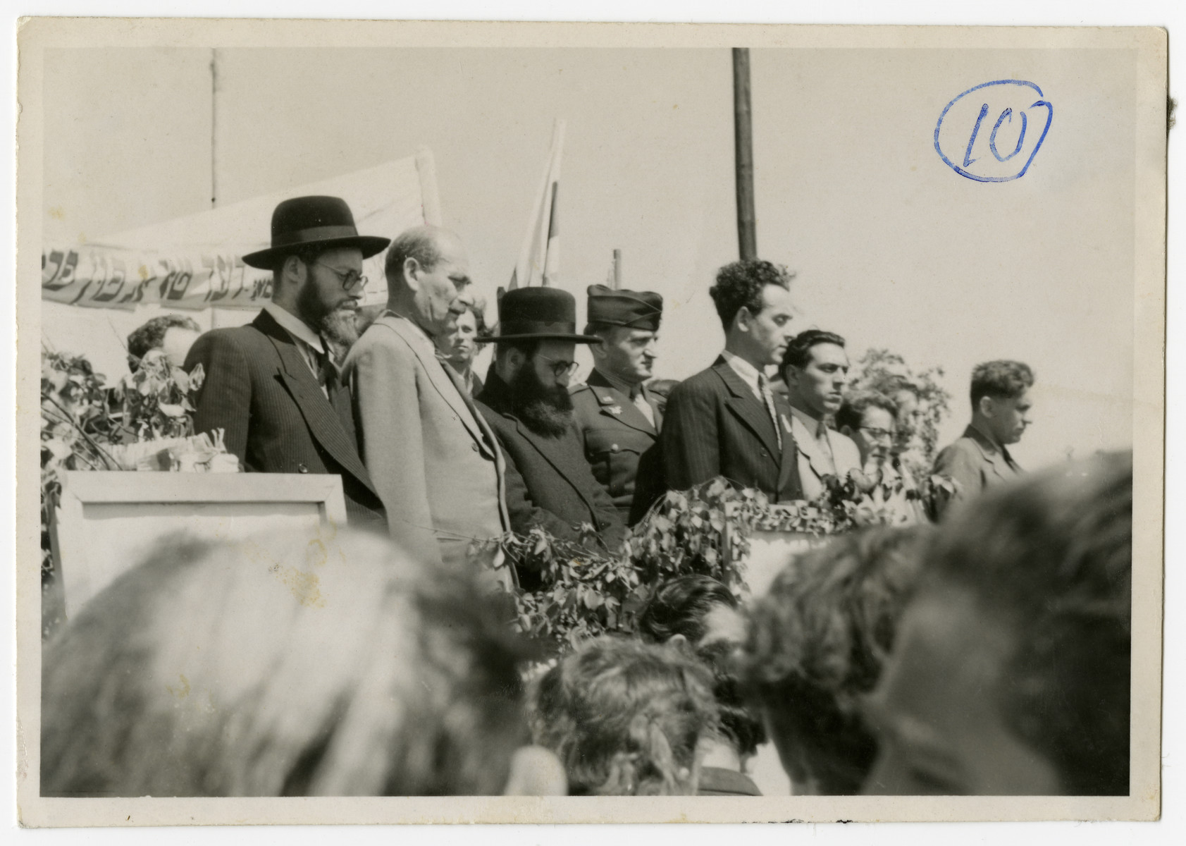 Solomon Manischewitz, standing center in a striped suit, leads a crowd assembled in singing the Hatikva on the day of the Proclamation of the State of Israel.