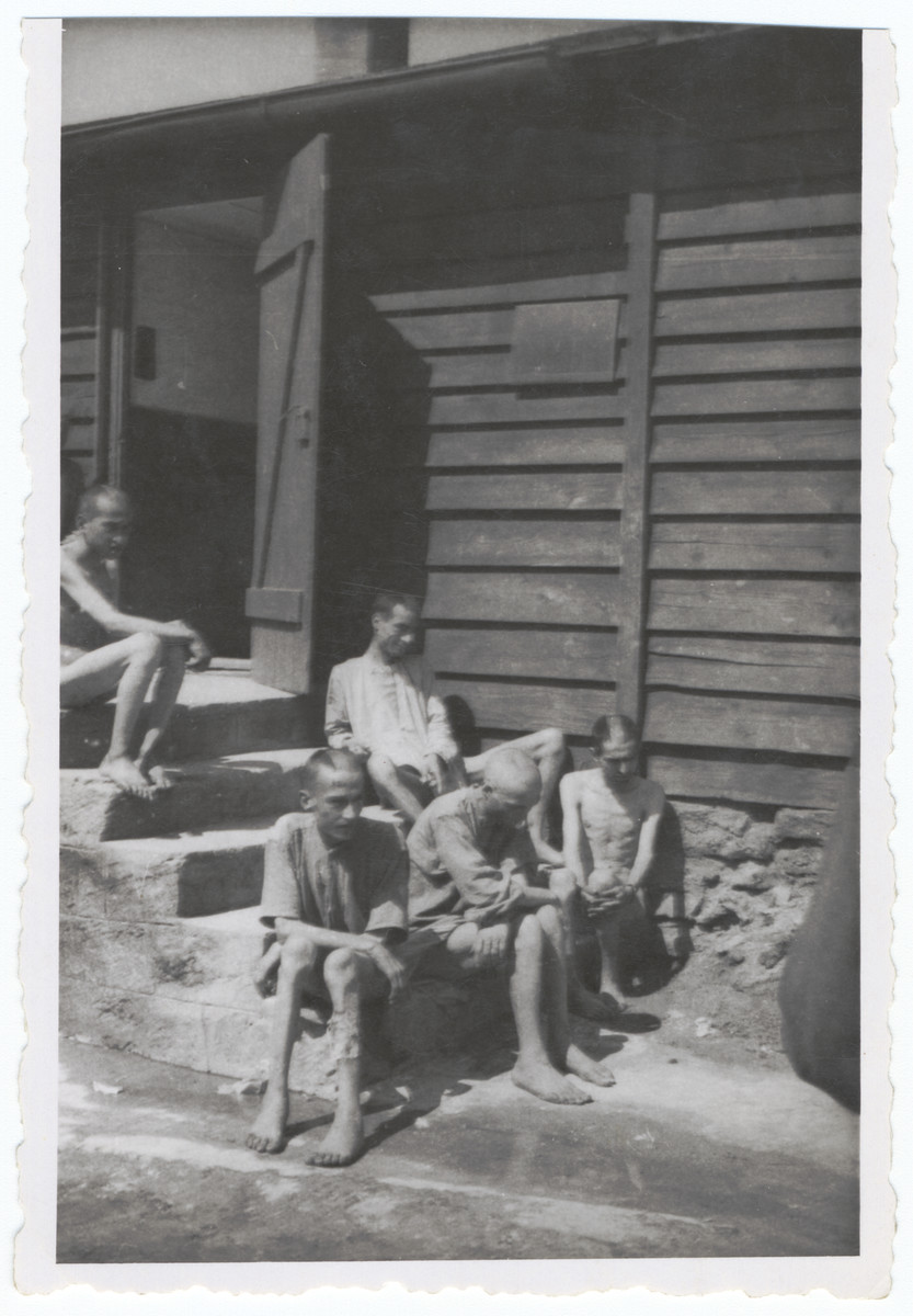 Survivors of the Gusen concentration camp rest on the outside steps of a barracks euphemistically called the Banhoff since the hospital barracks was the railway to heaven.