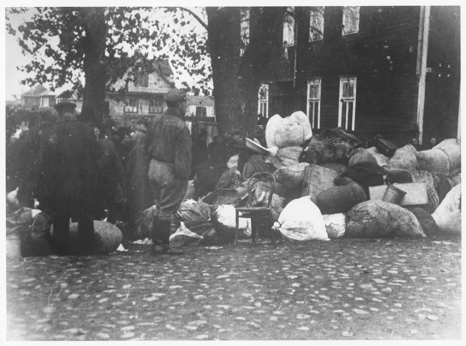 Residents of the Kovno ghetto view a pile of bundles left behind after the last deportation transport . 

The possessions that were left behind were taken over by the welfare department of the Jewish Council and distributed to the needy.